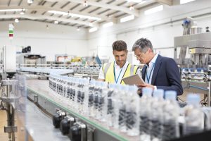 Supervisor and manager watching plastic bottles on conveyor belt Image provided