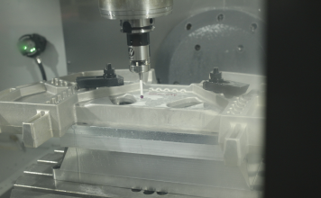 Customer image from Conturo Prototyping showing their use of Fusion 360 and the Fusion 360 Machining Extension. Image shows the inside of a CNC machine as it uses a spindle-mounted probe to take measurements on a component.