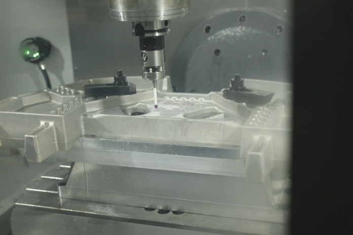 Customer image from Conturo Prototyping showing their use of Fusion 360 and the Fusion 360 Machining Extension. Image shows the inside of a CNC machine as it uses a spindle-mounted probe to take measurements on a component.
